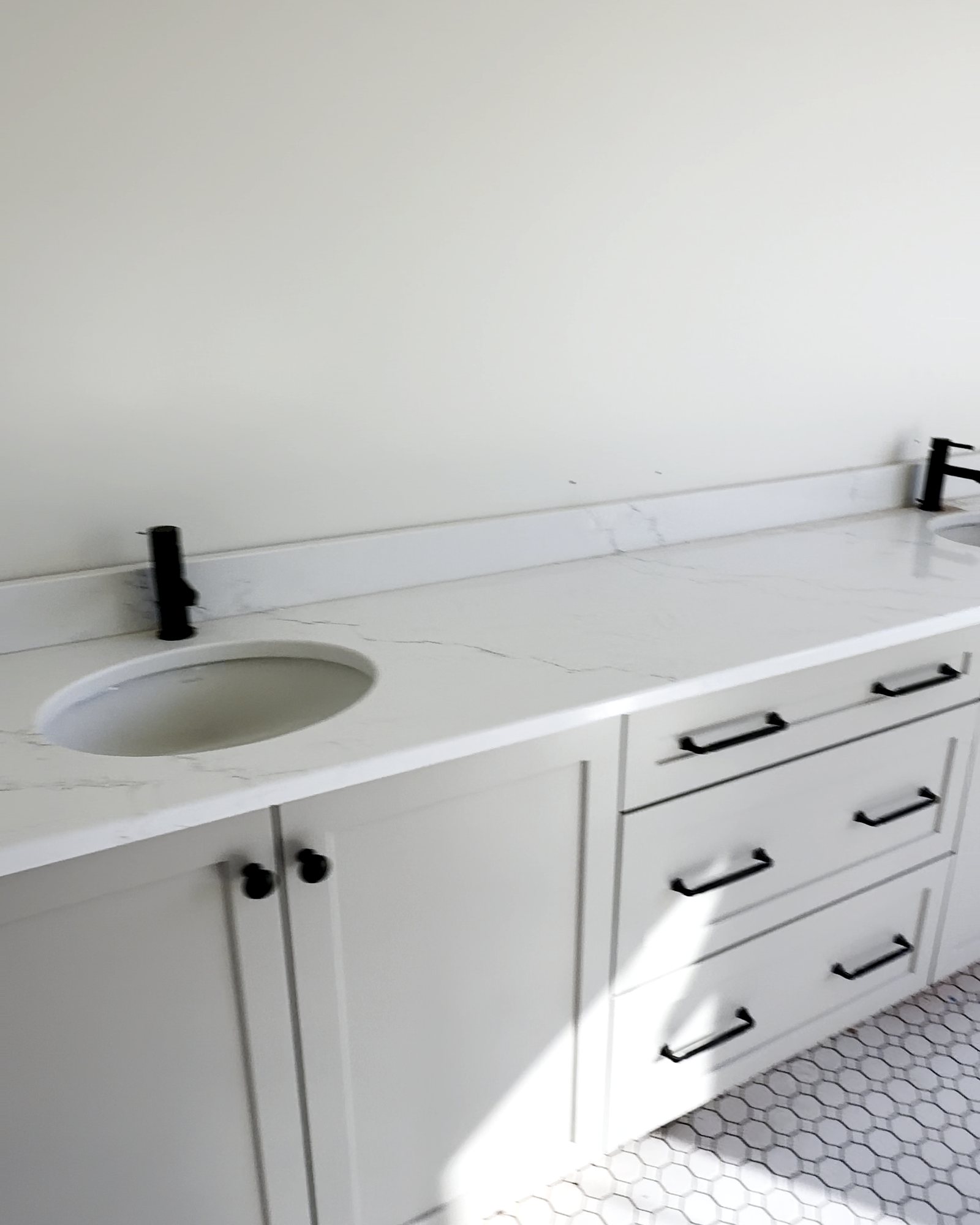 Bathroom vanity with quartz top, black fixtures and hex tile floor