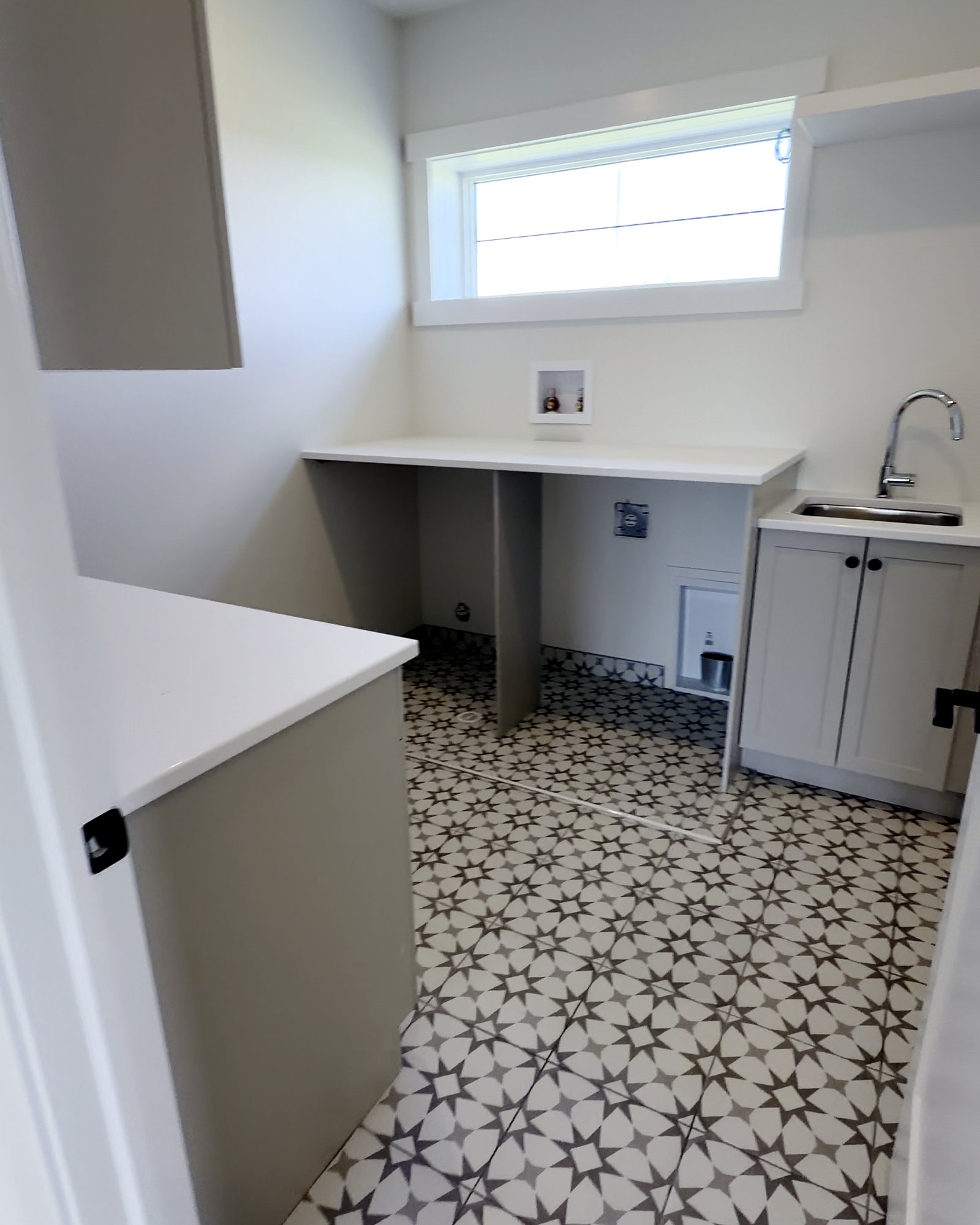 Laundry room with patterned tile floor and clean cabinets